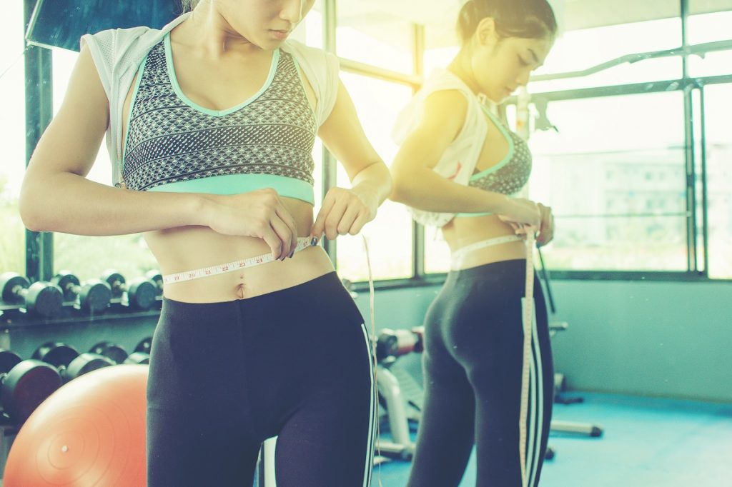 Woman in sportswear measuring her waist