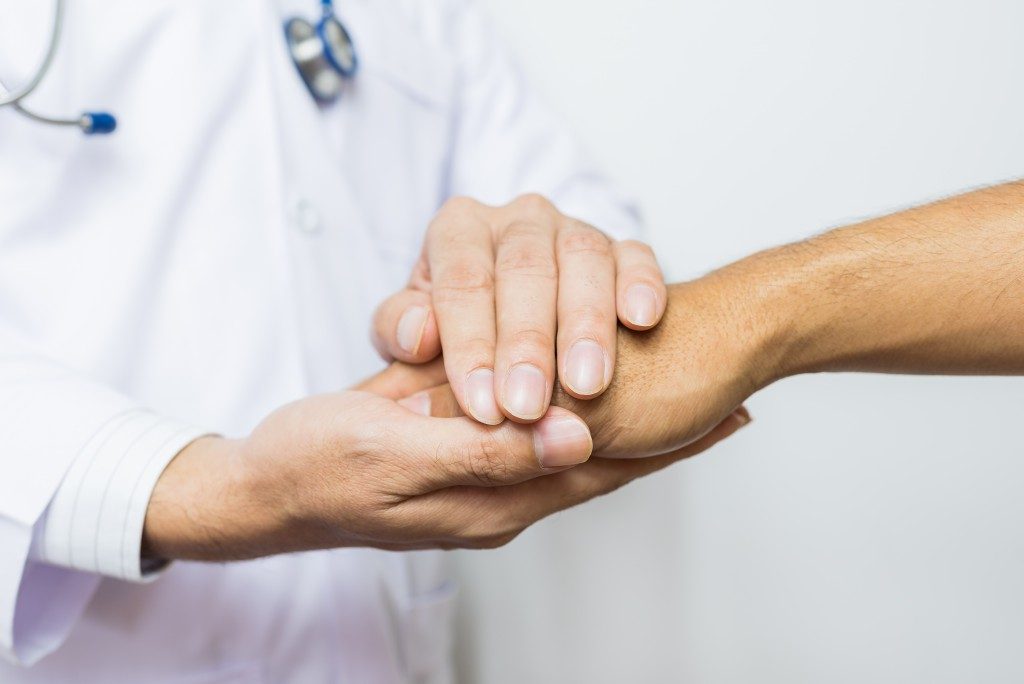 Doctor holding a thankful patient's hand