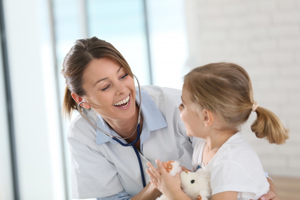 Doctor checking little girl's heartbeat