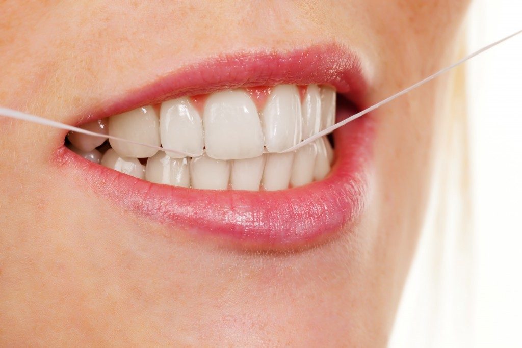 A young woman uses dental floss to clean your teeth