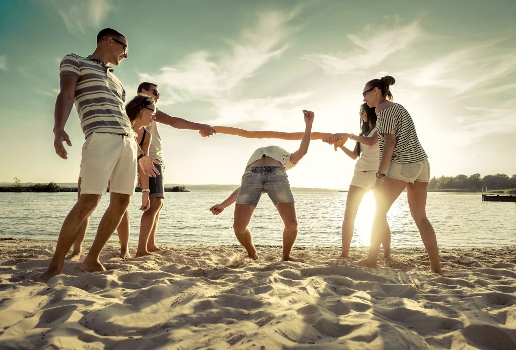 Friends funny game on the beach under sunset sunlight