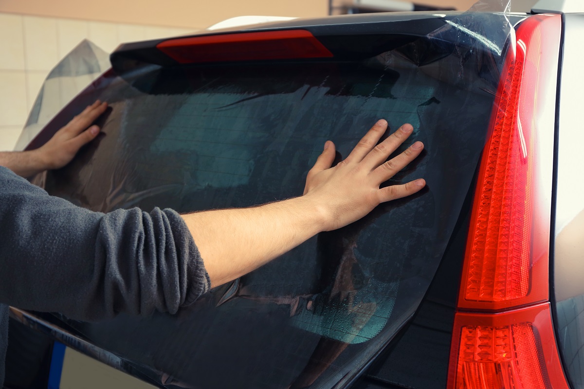 man wiping his car's tinted window