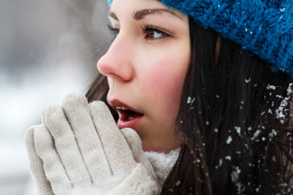 woman breathe with warm air on her frozen hands