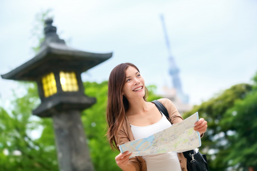 Asian tourist woman with map searching for directions with the Tokyo Skytree tower in the background
