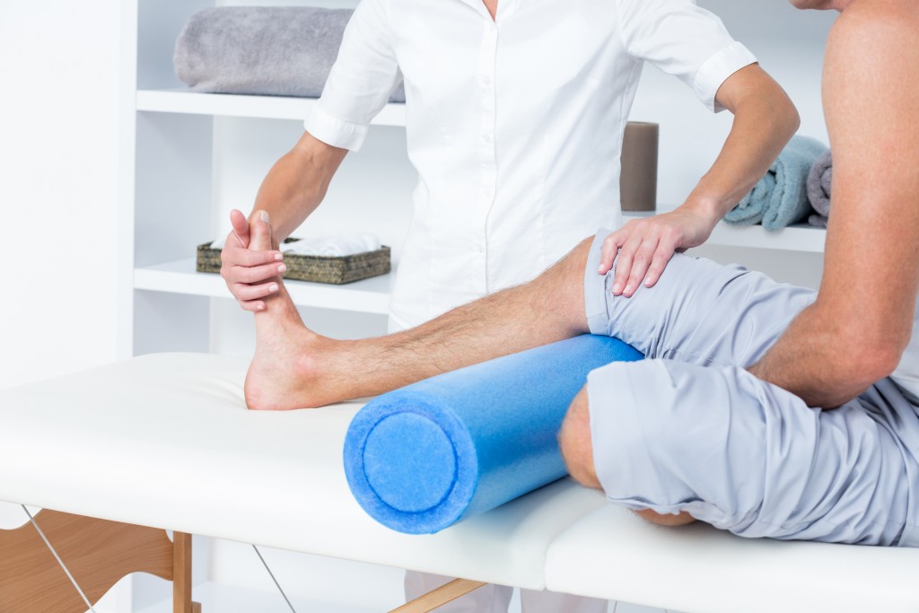 Doctor examining her patient leg in medical office