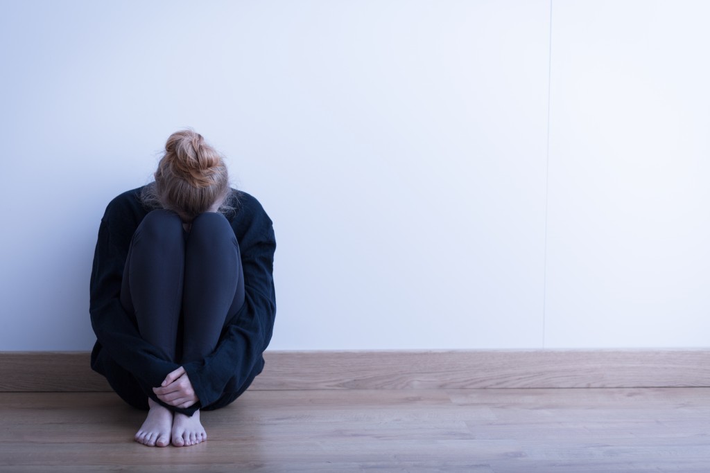 woman sitting on the floor, head bent down