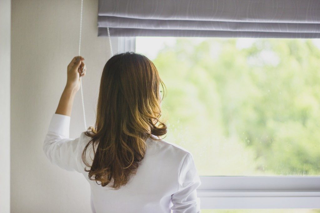 woman opening blinds