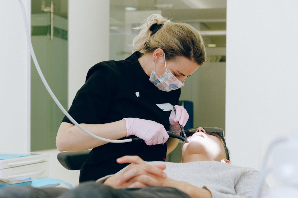 dentist cleaning the teeth of her patient