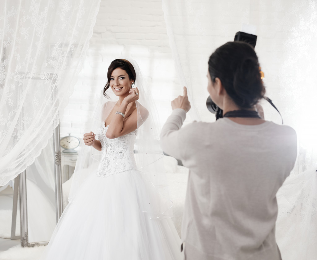 Female photographer photographing beautiful happy bride indoor