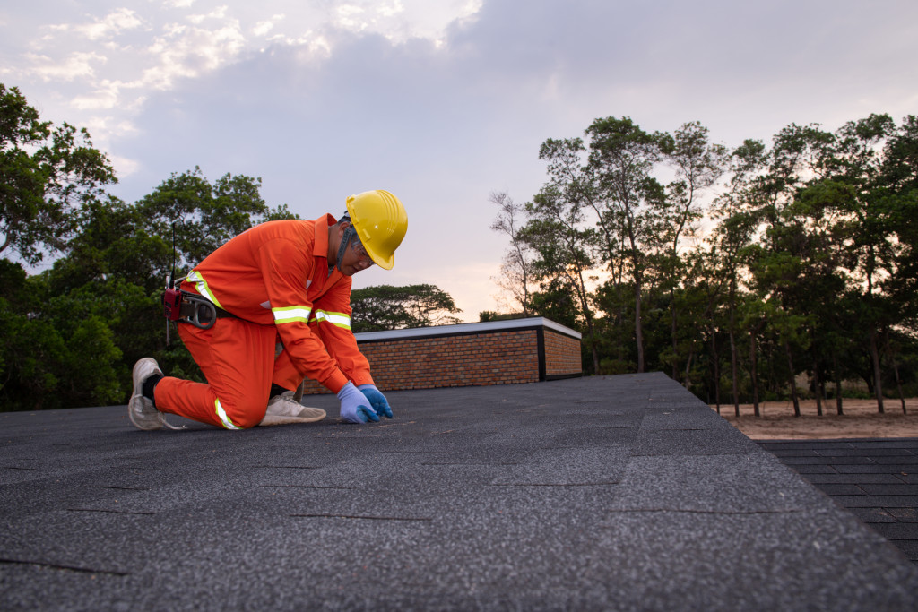 Roofer worker in special protective work wear and gloves,repairing the roof of a home