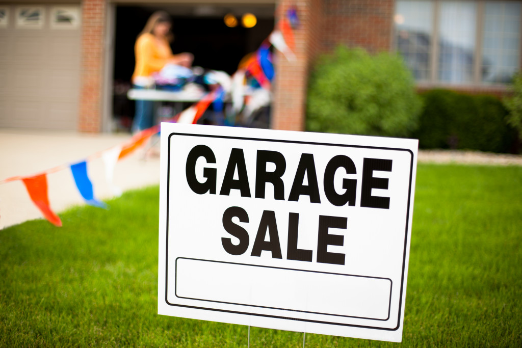 A garage sale sign in front of a suburban home yard