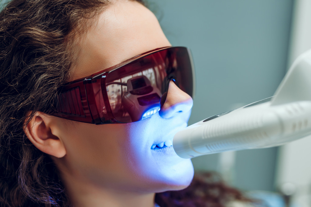 a female using blue light too whiten teeth