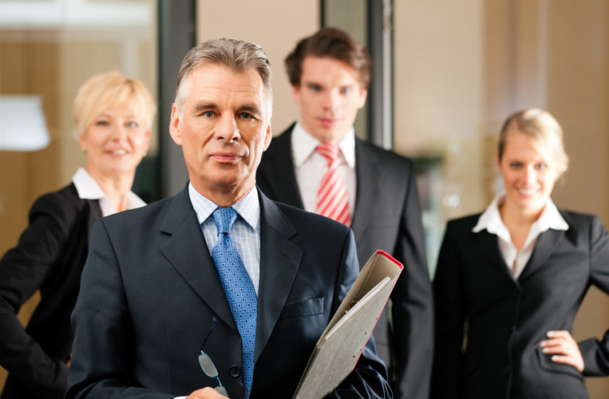 Business - team in an office; the senior executive is standing in front
