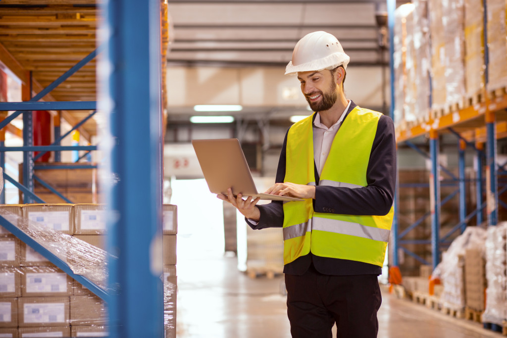 man using a laptop t check inventory of warehouse