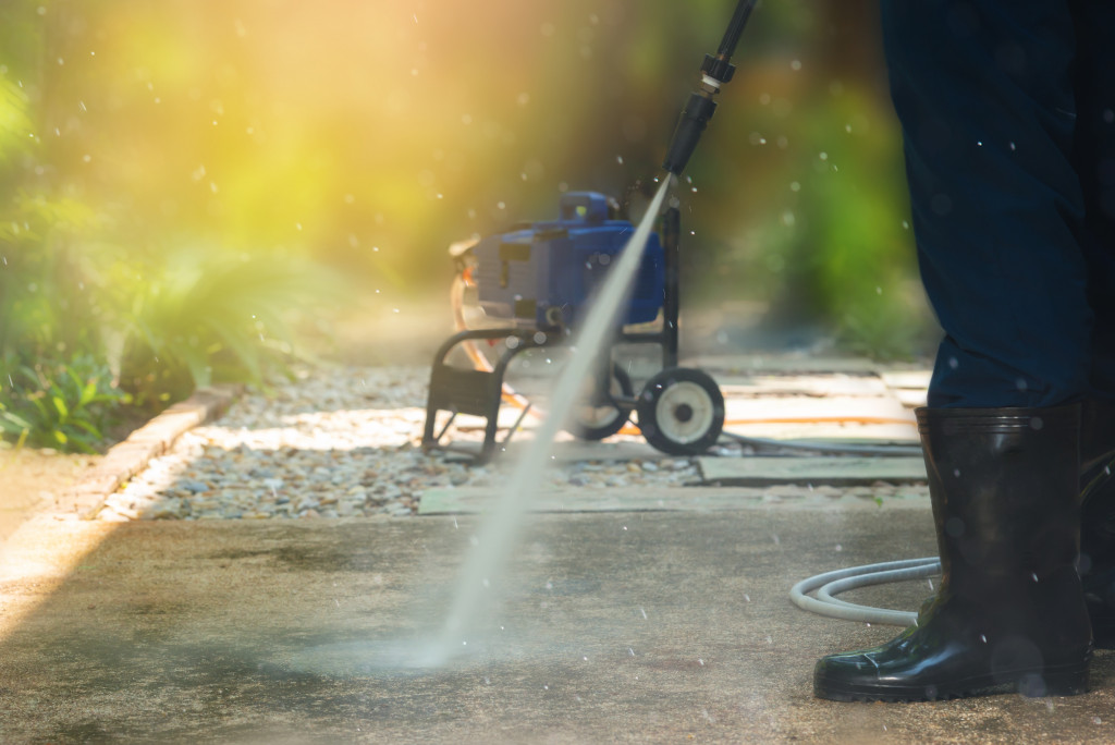 a worker is using a pressure washer to clean the walkway