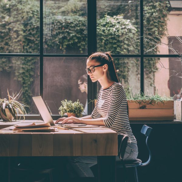 A woman working remotely on her laptop at a cafe