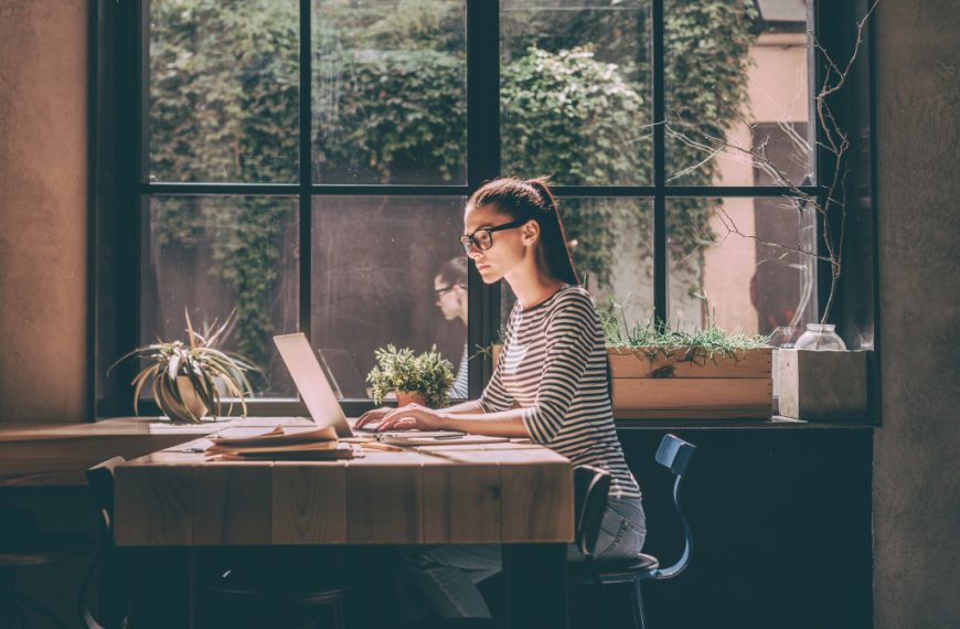 A woman working remotely on her laptop at a cafe