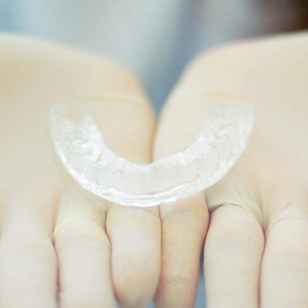 A Clear Retainer on a Person's Hands Wearing Gloves