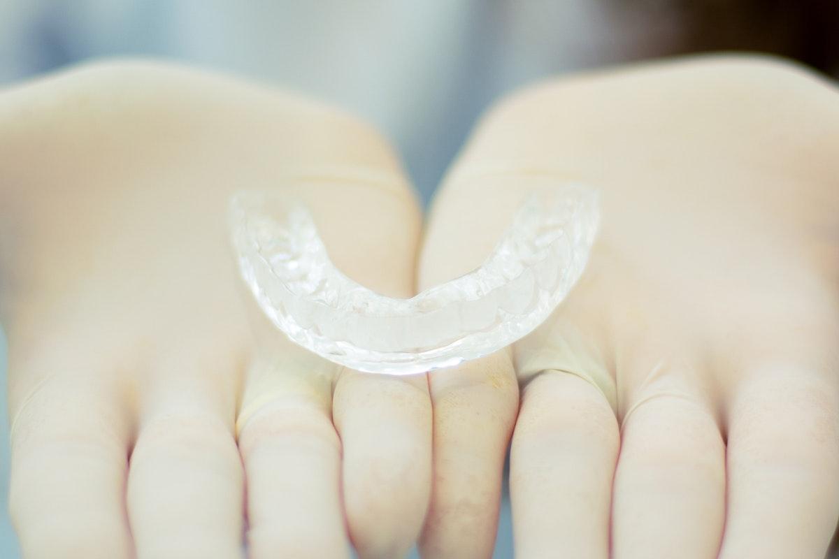 A Clear Retainer on a Person's Hands Wearing Gloves